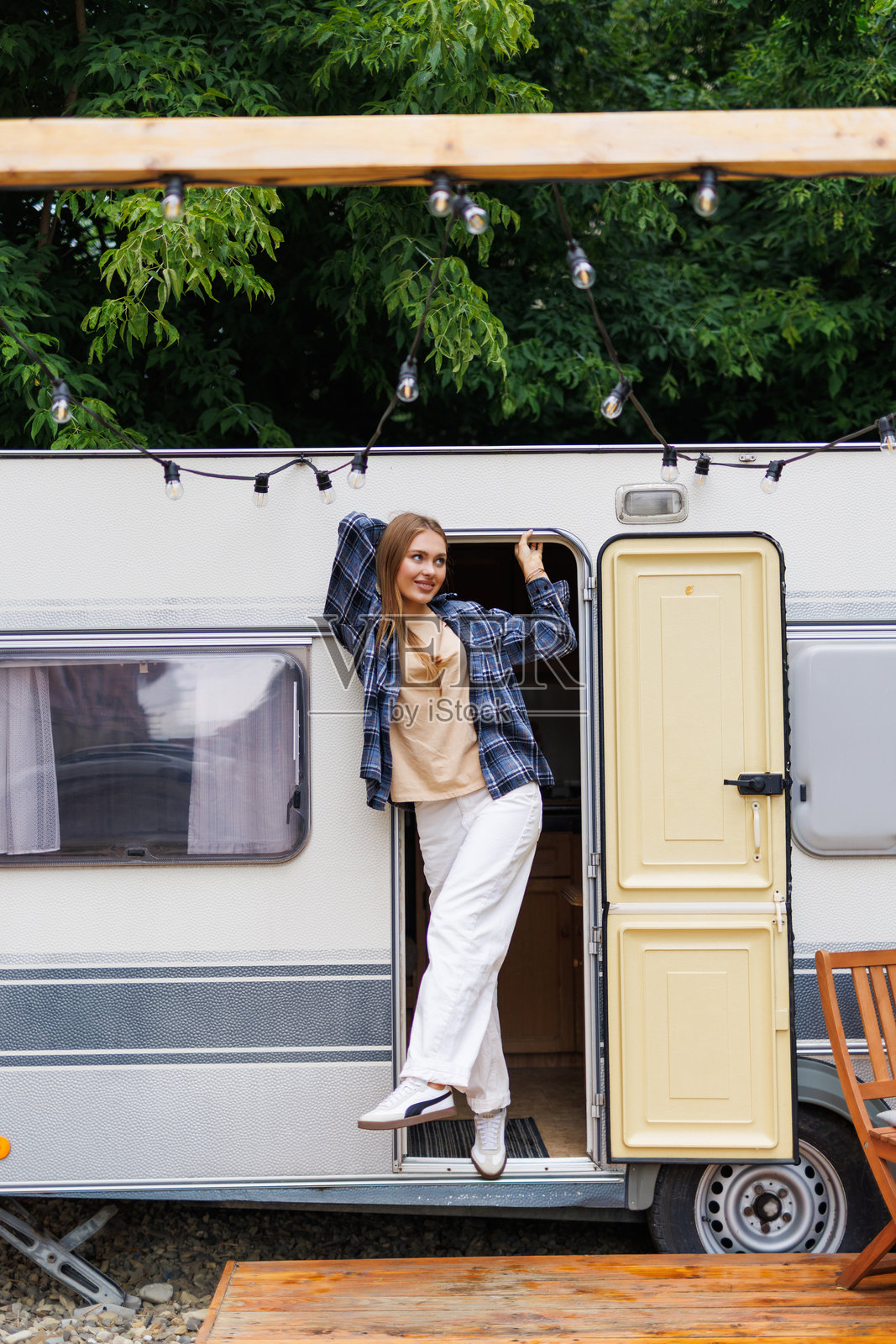 快乐的年轻女子在旅行中站在她的露营车前照片摄影图片