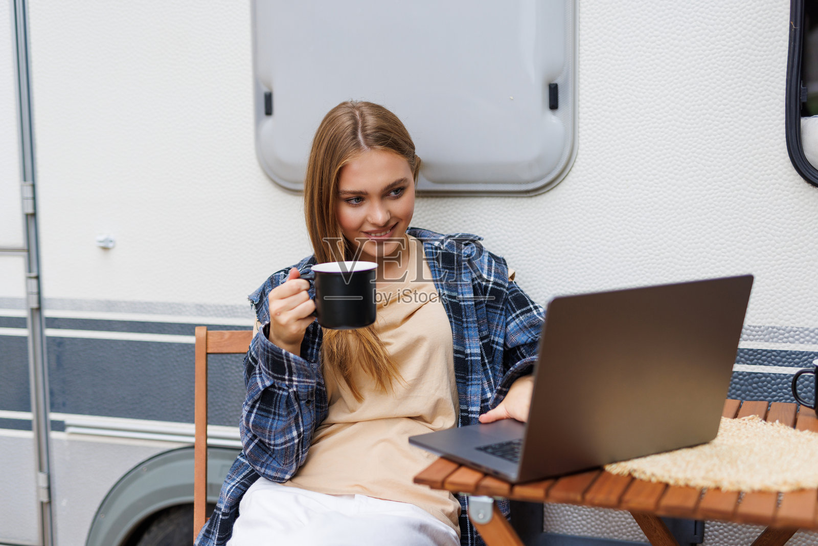 年轻女子坐在露营车前,看着笔记本电脑照片摄影图片