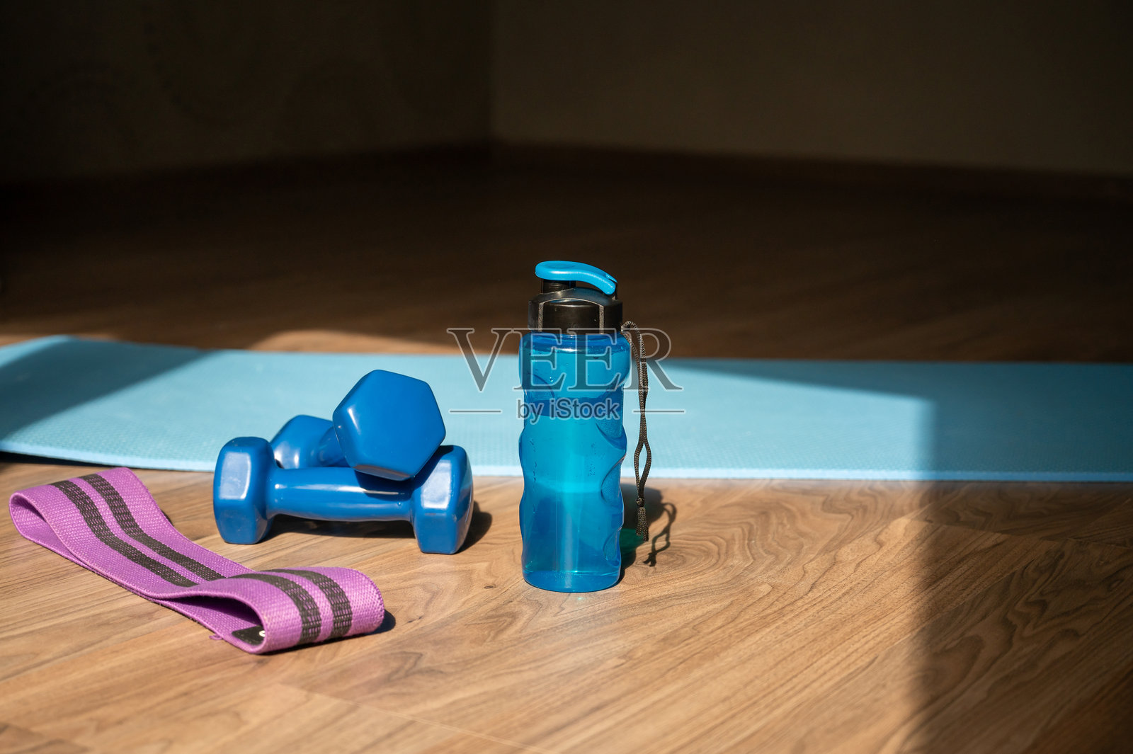 家里的瑜伽垫上放着哑铃、弹力带和水瓶照片摄影图片