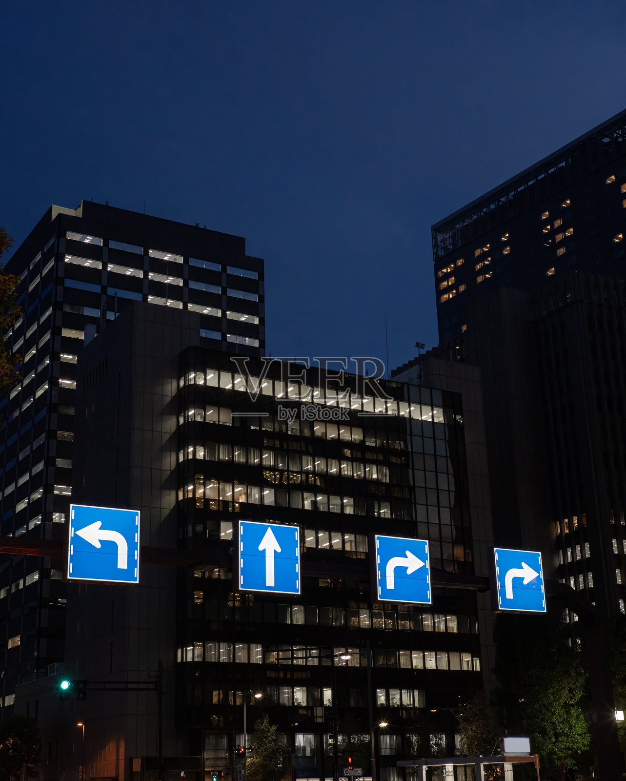 黄昏时分的蓝色方向指示交通标志和城市建筑照片摄影图片