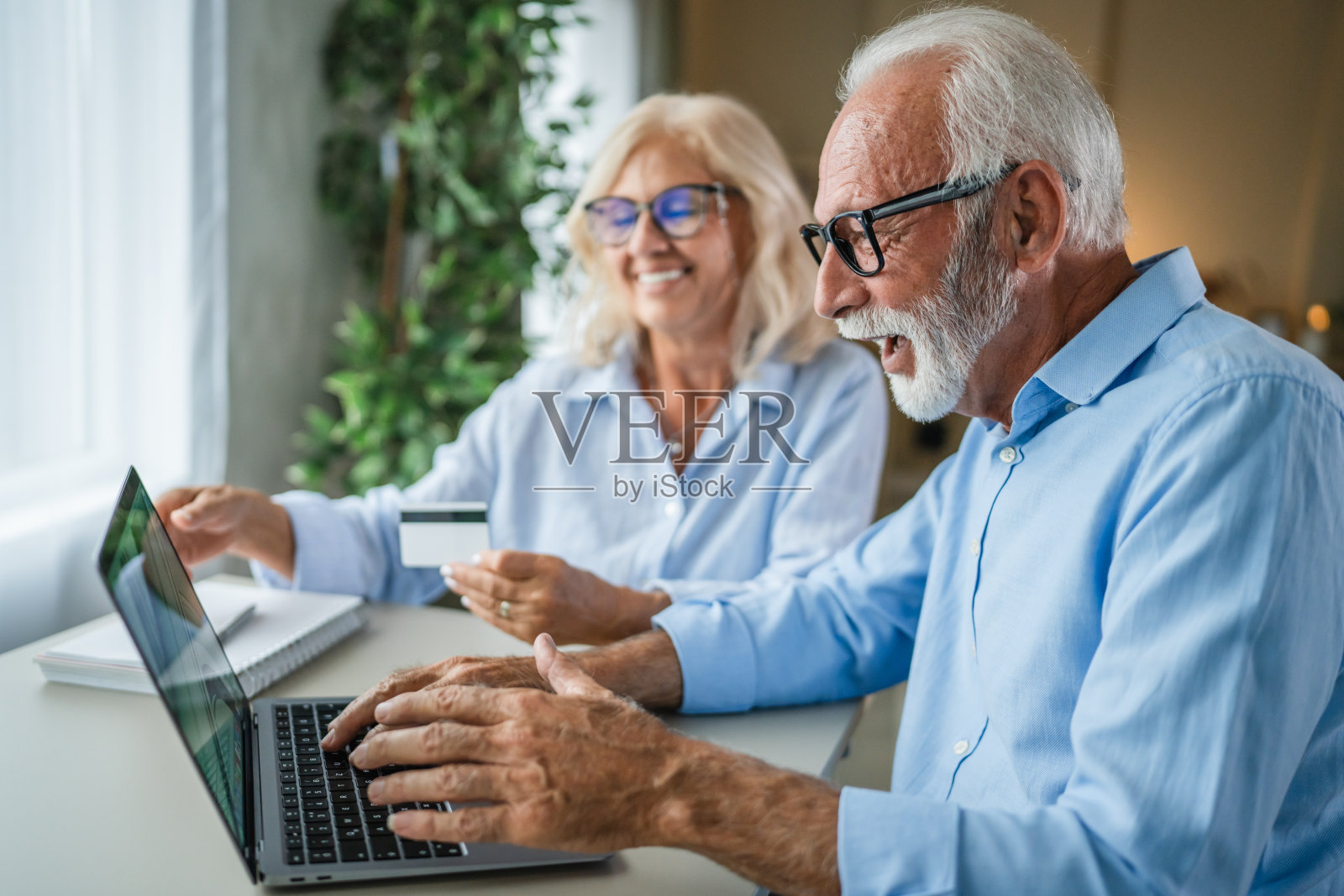 老年夫妇在笔记本电脑上刷信用卡享受在线购物的乐趣照片摄影图片