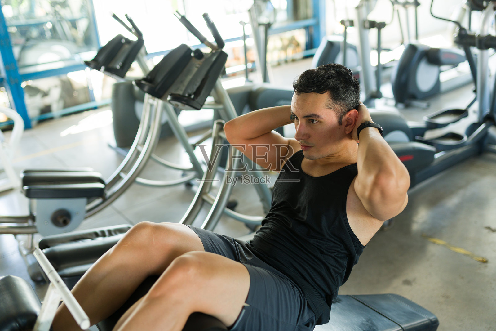 男人在健身房锻炼腹肌做仰卧起坐照片摄影图片