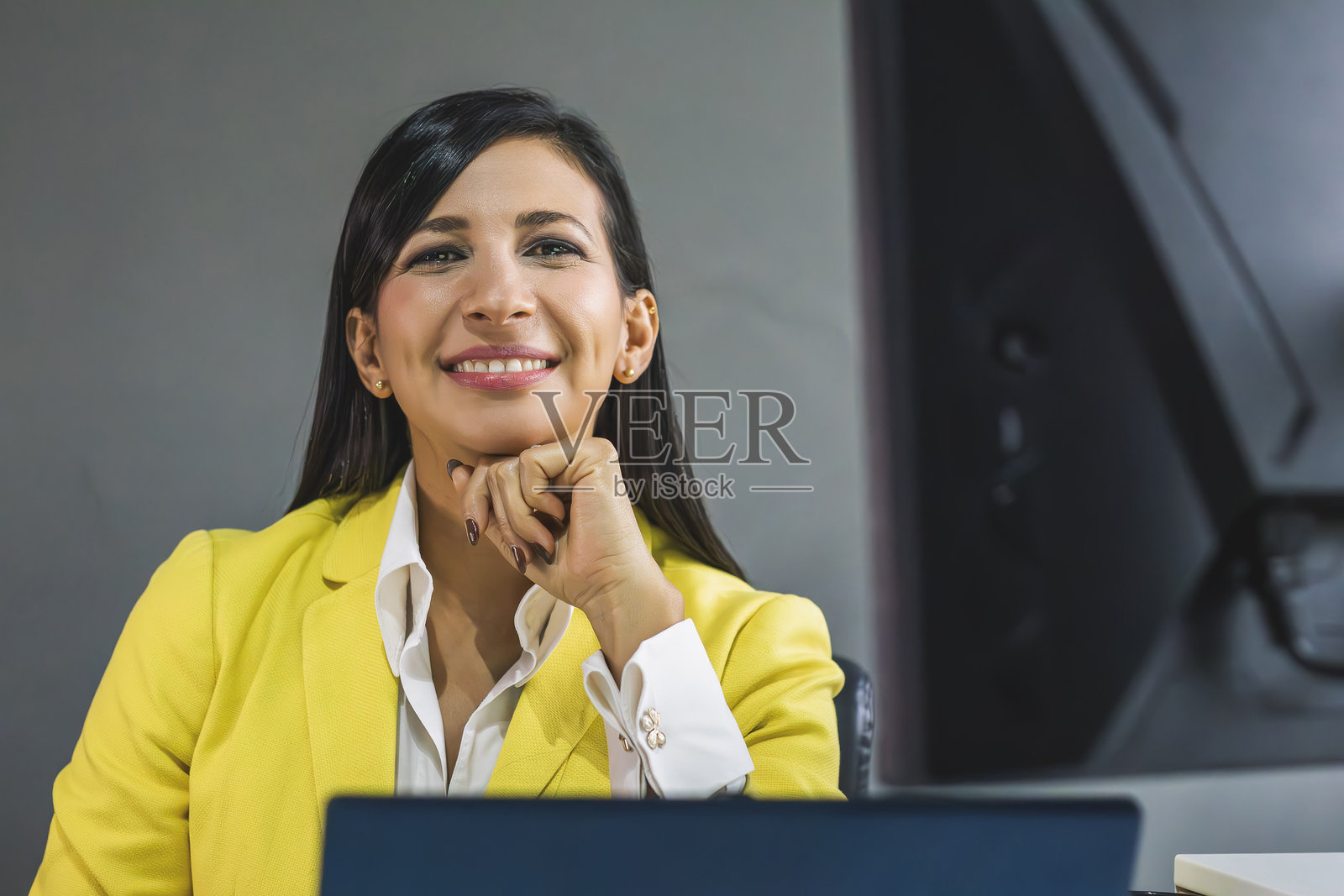 自信的拉丁裔女商人的肖像,她面带微笑地使用电脑。照片摄影图片