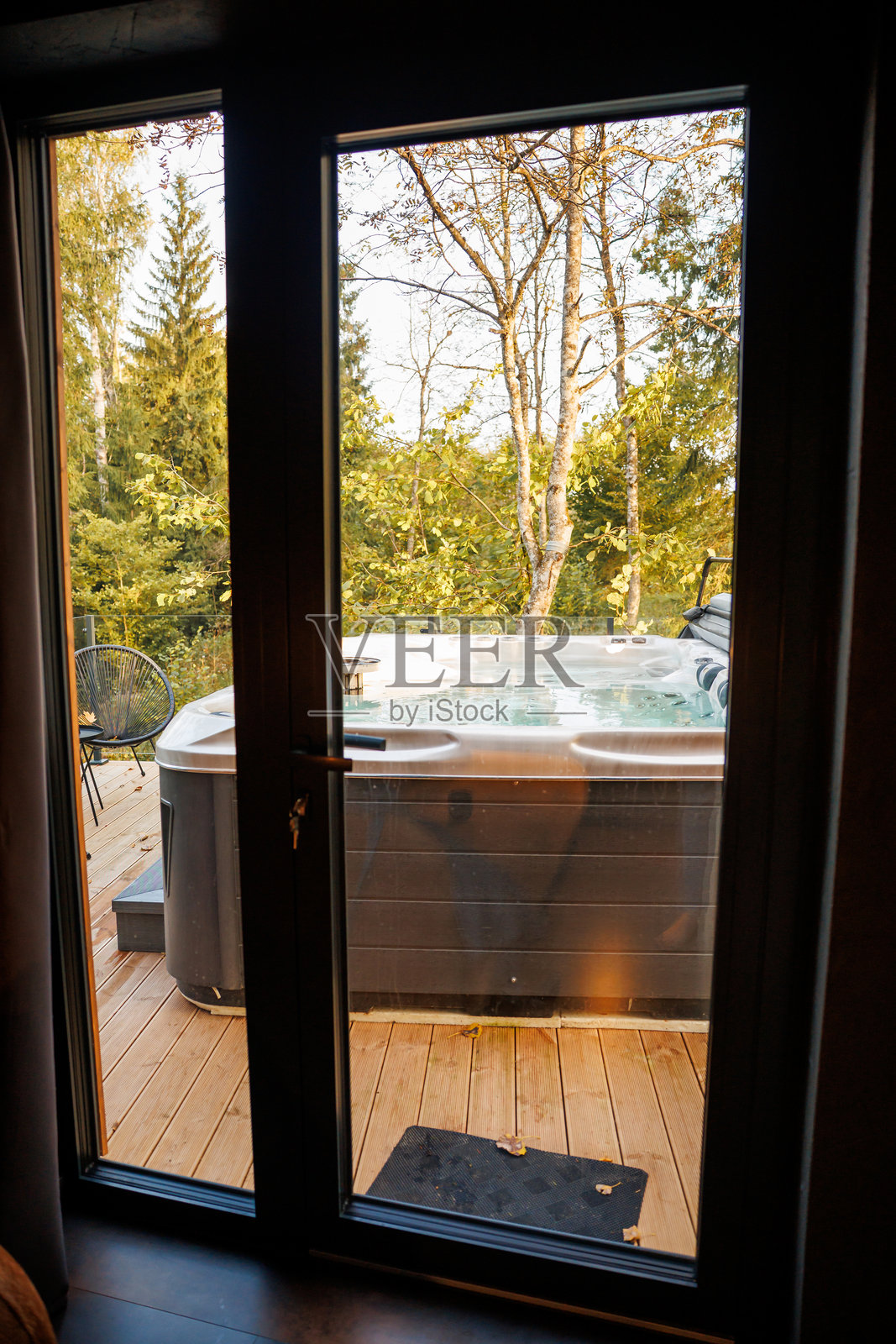 透过玻璃门看到的户外露台,配有热水浴缸和椅子照片摄影图片