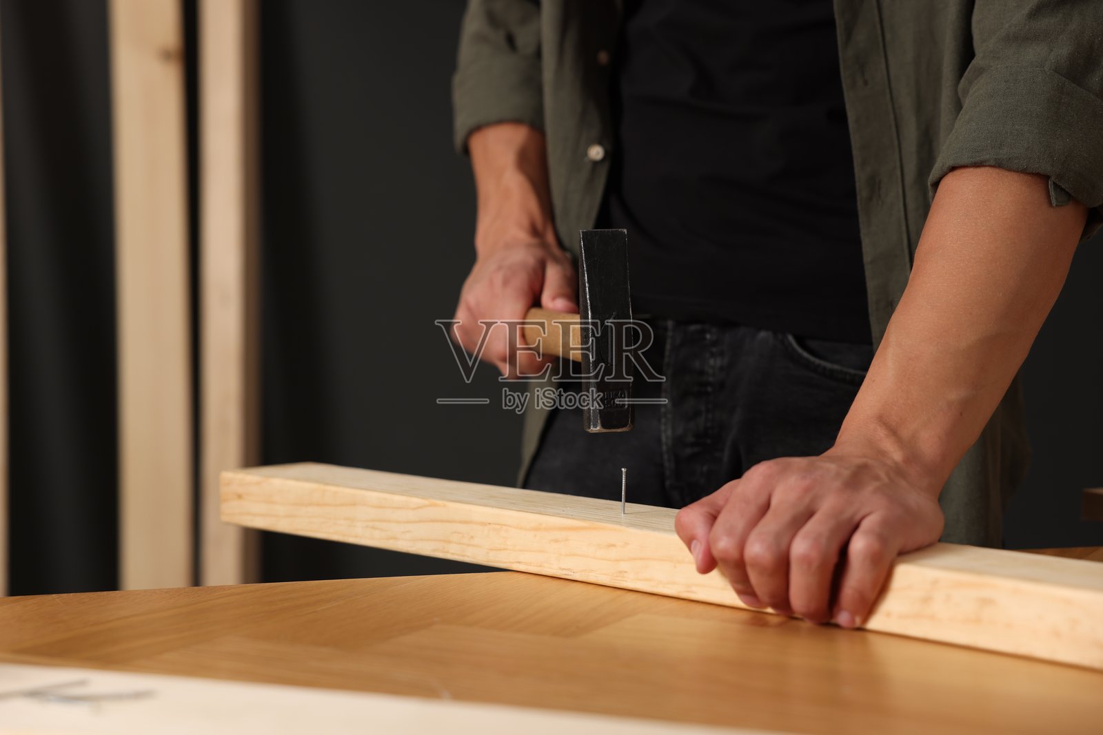 特写:室内男子将钉子钉入木板照片摄影图片