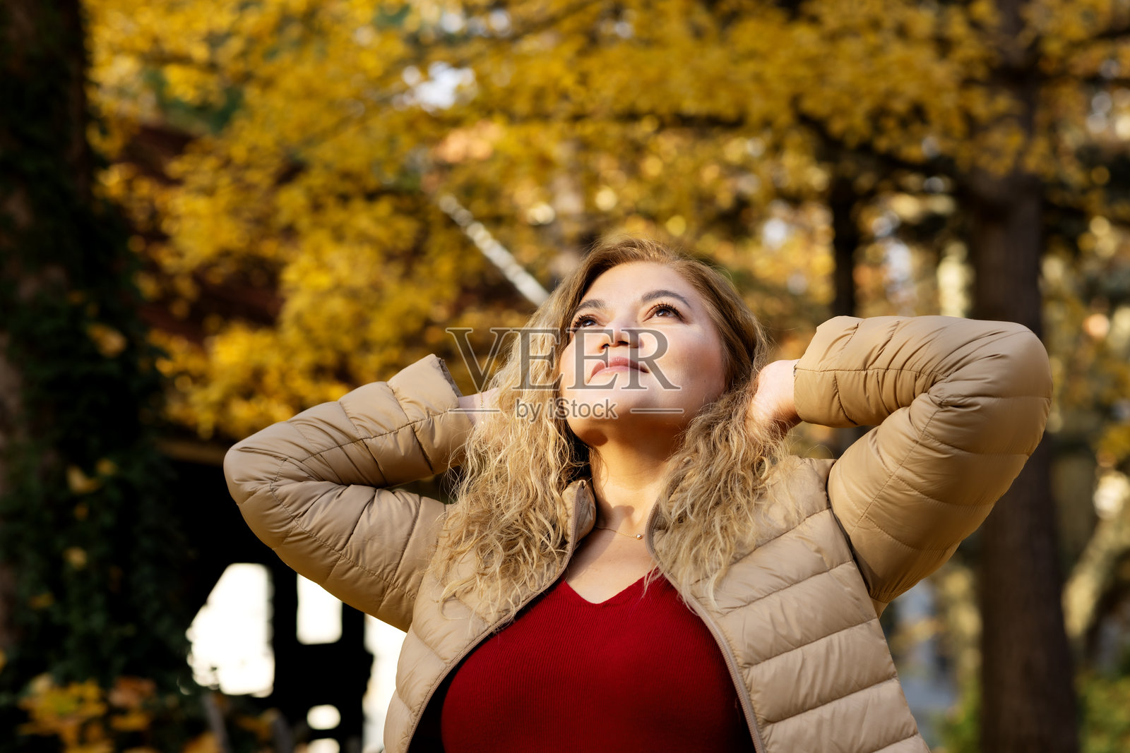 一位留着长卷发的亚洲女性在秋日里享受温暖的阳光。照片摄影图片