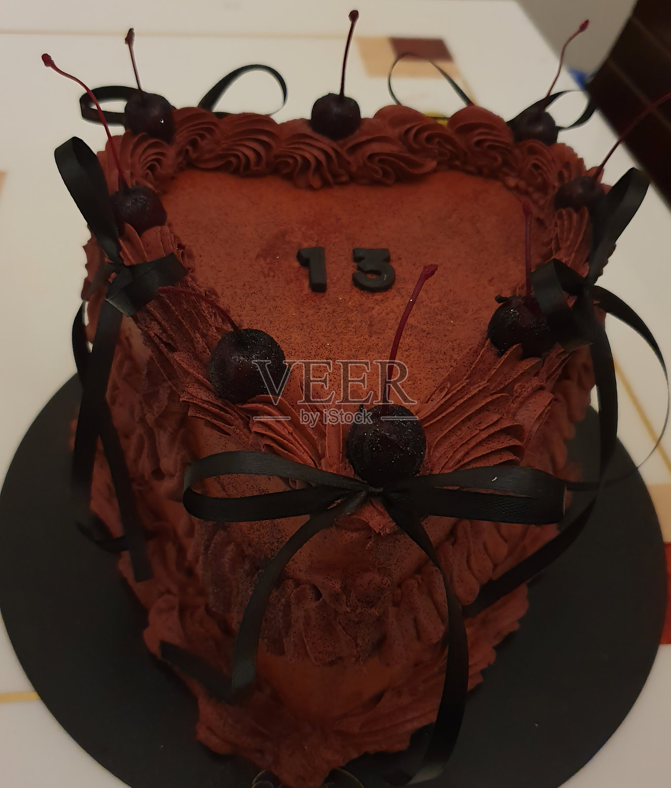 一款优雅的心形蛋糕,覆盖着光滑的勃艮第糖霜,并饰以多汁的樱桃和丝带。照片摄影图片