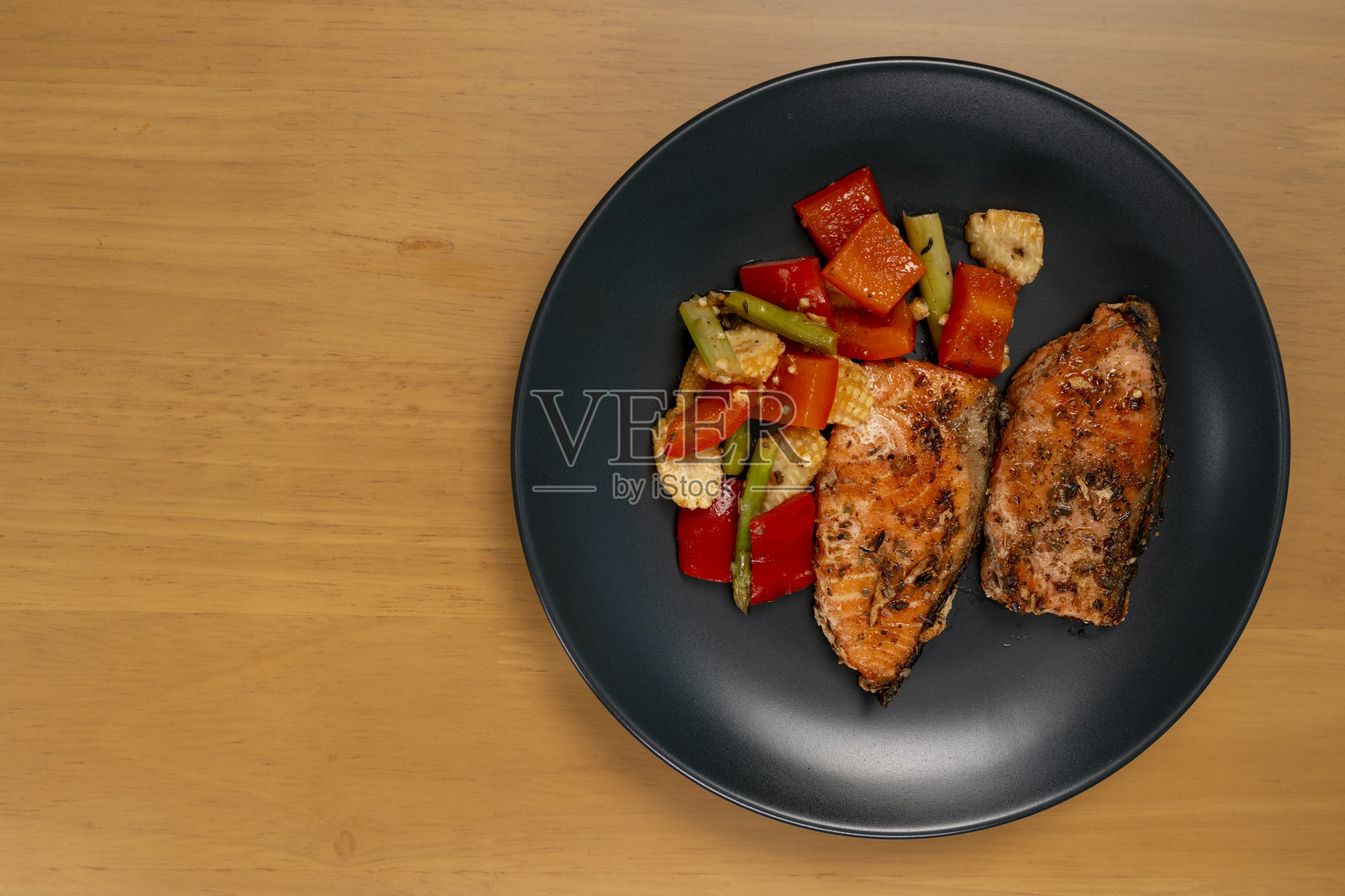 烤或炸三文鱼排配新鲜蔬菜,摆放在盘中,俯视木桌。照片摄影图片