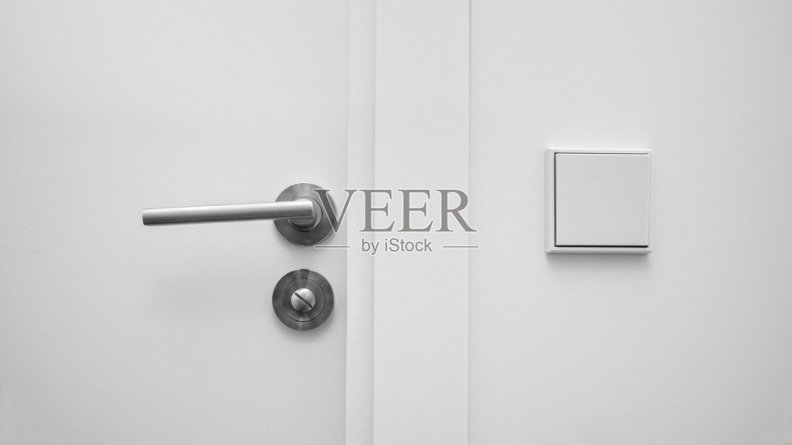 简约白色墙壁,配有现代金属门把手和灯开关,现代设计室内细节。照片摄影图片