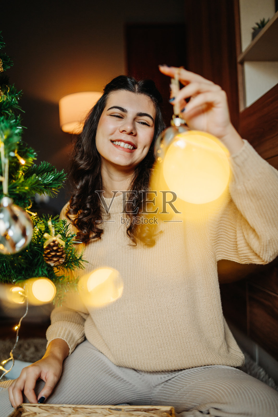 年轻的高加索女性正在给圣诞树挂上圣诞装饰品照片摄影图片