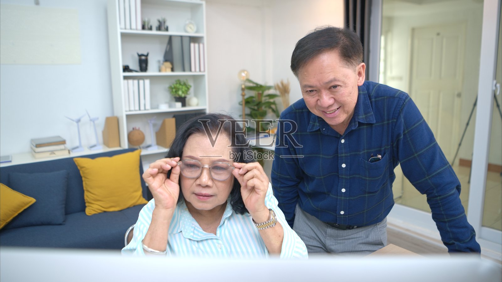 节假日,一对老年夫妇在家放松,使用电脑浏览网页,享受悠闲时光。照片摄影图片