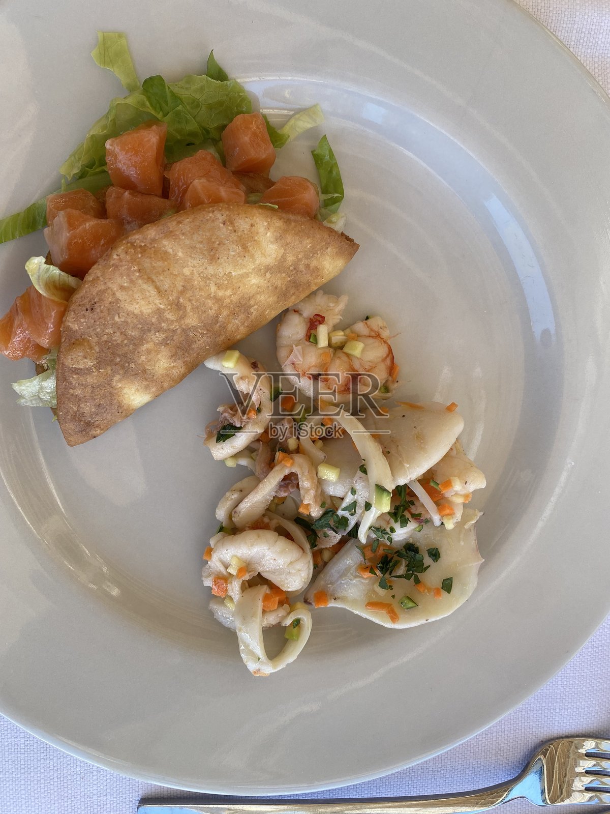 三文鱼塔可和海鲜沙拉盛放在白色餐厅餐盘上,这是佩斯卡拉的意式新鲜美食照片摄影图片