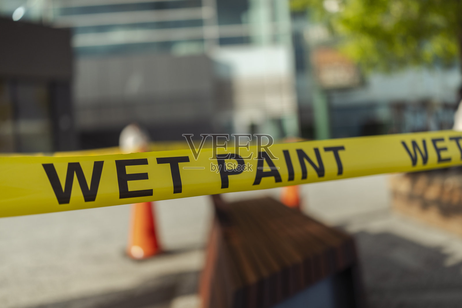 户外黄色湿油漆警示带,靠近城市长椅和交通锥照片摄影图片