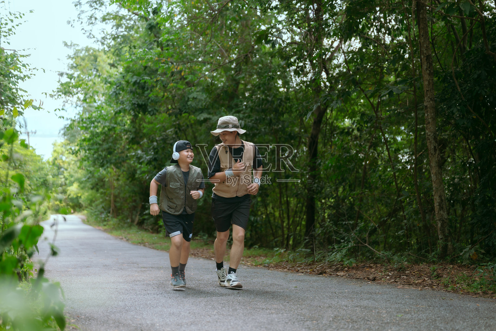 父子在阳光明媚的下午,在森林小径上慢跑,享受着宝贵的亲子时光。照片摄影图片