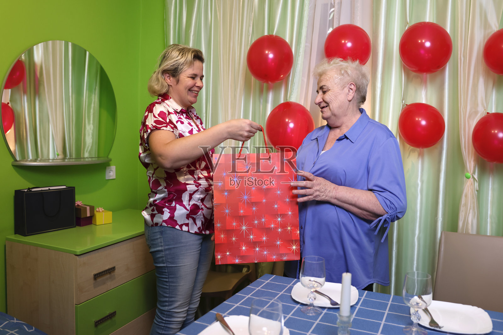 女儿祝奶奶生日快乐并送上礼物。柔和的光线。照片摄影图片