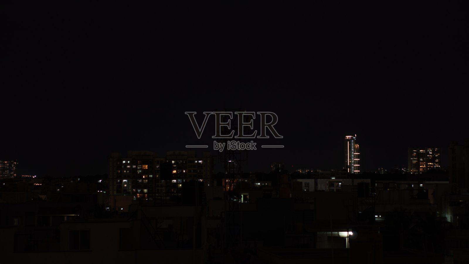 黄昏时分,城市里高耸的住宅楼在夜空中亮起。照片摄影图片