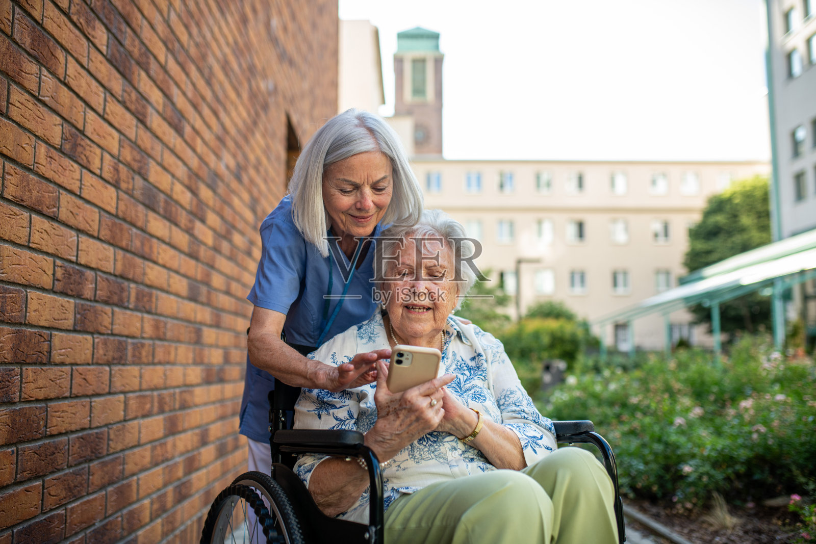 一名护士帮助一位老年患者在手机上查找东西。照片摄影图片