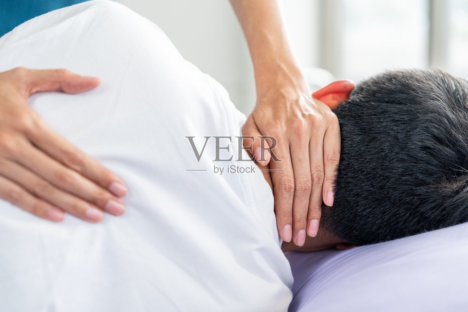 物理治疗。女护士协助年轻男子从脊柱损伤中恢复,并提供骨科按摩。骨科保健和脊椎治疗师与患者一起进行物理治疗康复。照片摄影图片