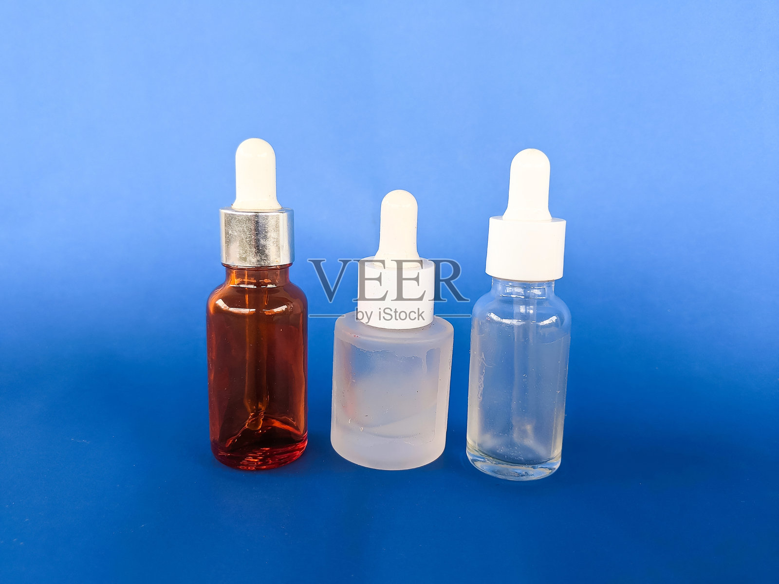 蓝背景下的精华液玻璃瓶照片摄影图片