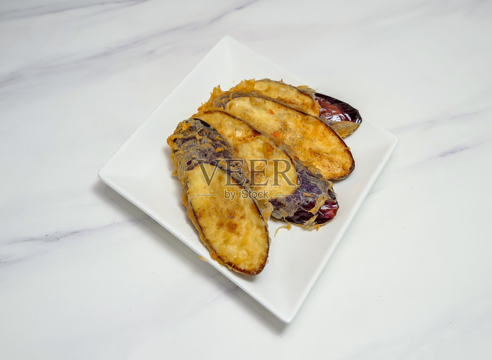 白色盘子里的炸椒盐茄子片,大理石背景上,素食配菜俯视图照片摄影图片