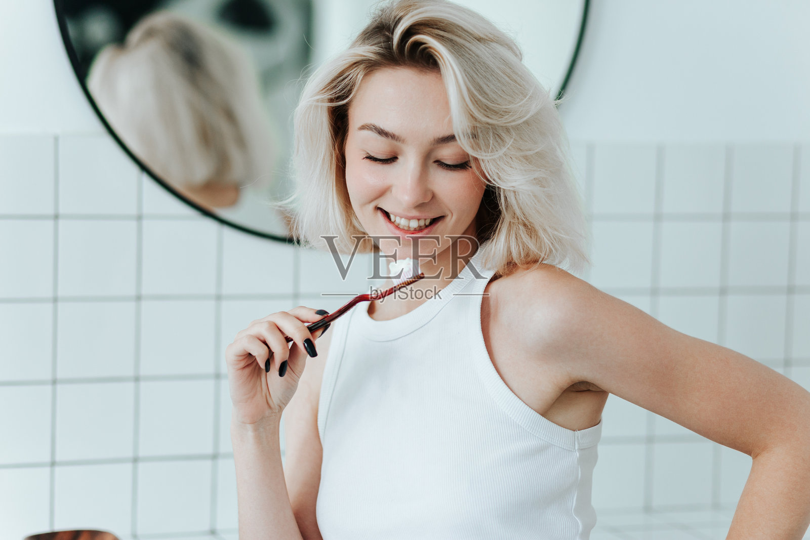 微笑的金发女子手中拿着牙膏的牙刷特写照片摄影图片