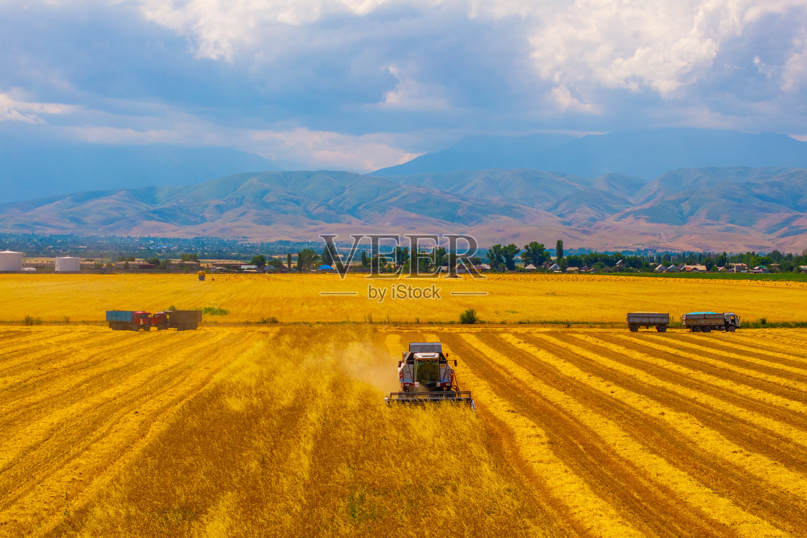 联合收割机在宁静的乡村田野中作业,背景是连绵的山峦。照片摄影图片