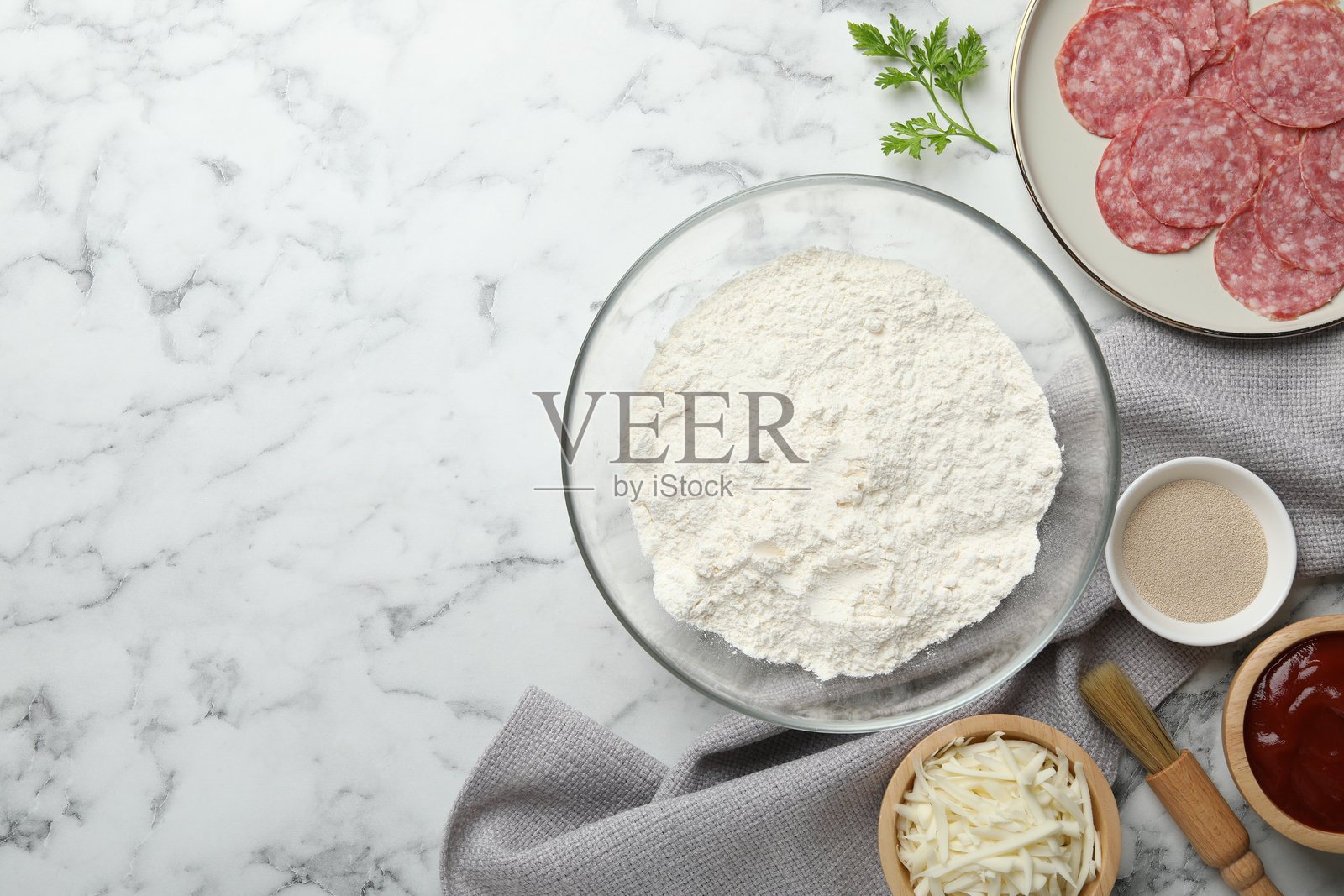 制作卡尔佐内披萨。白色大理石桌面上摆放着各种食材,俯视角度。留有空白文本区域。照片摄影图片