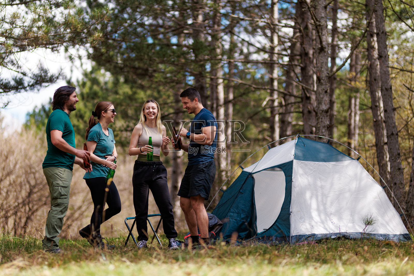 和朋友们在阳光明媚的白天,于林区举杯畅饮,欢声笑语的露营之旅照片摄影图片