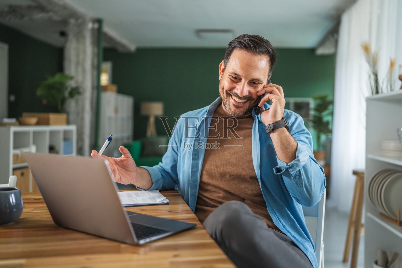 居家办公的男士,用笔记本电脑和手机处理业务照片摄影图片