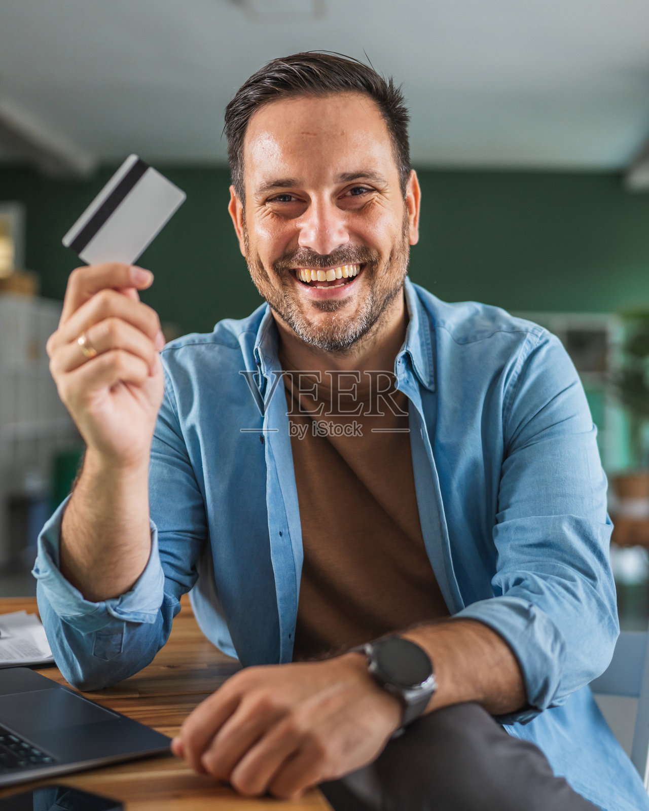 快乐的男人在家通过信用卡进行在线购物照片摄影图片