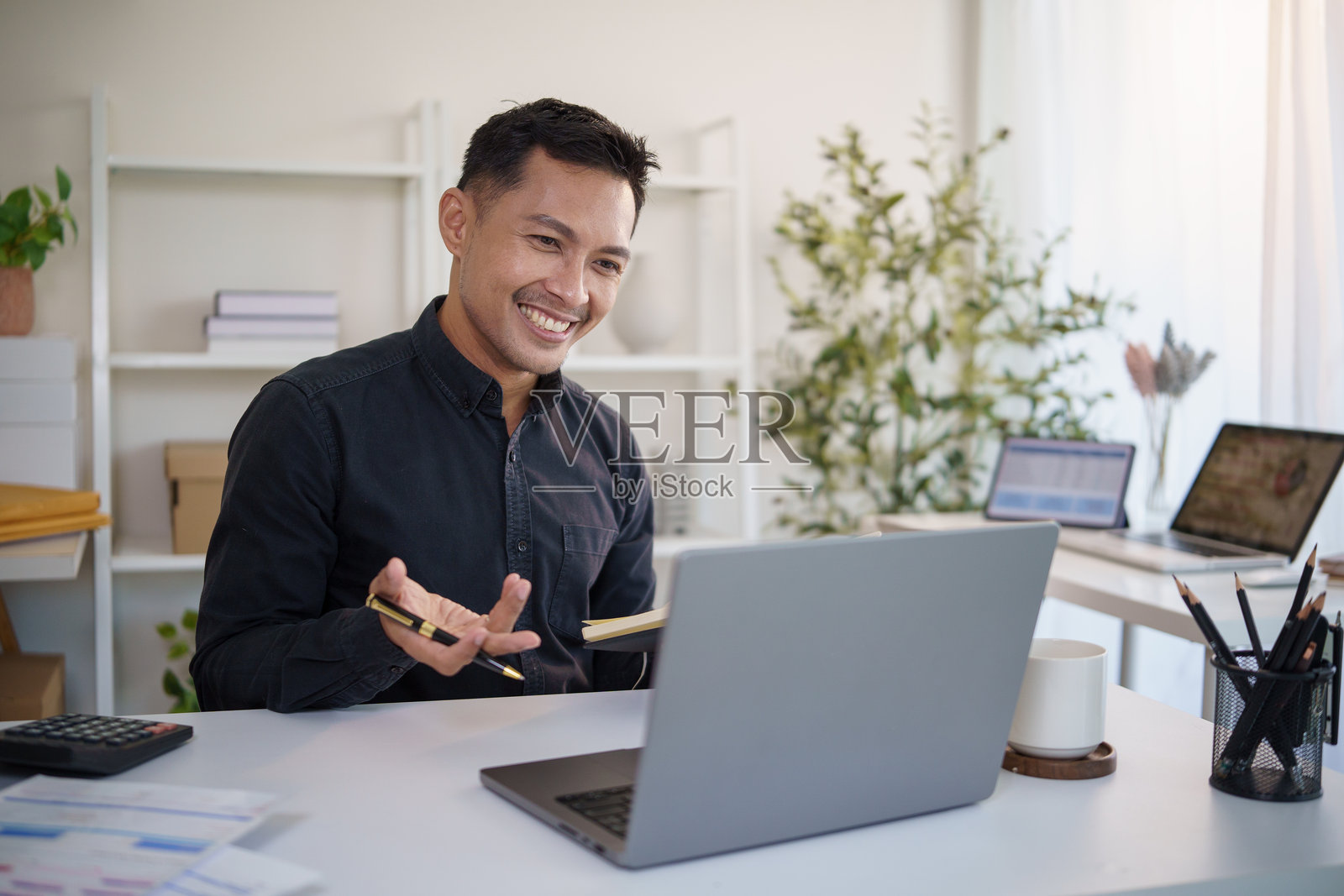 一位快乐的商人在现代办公室里通过在线方式进行虚拟会议讨论。照片摄影图片