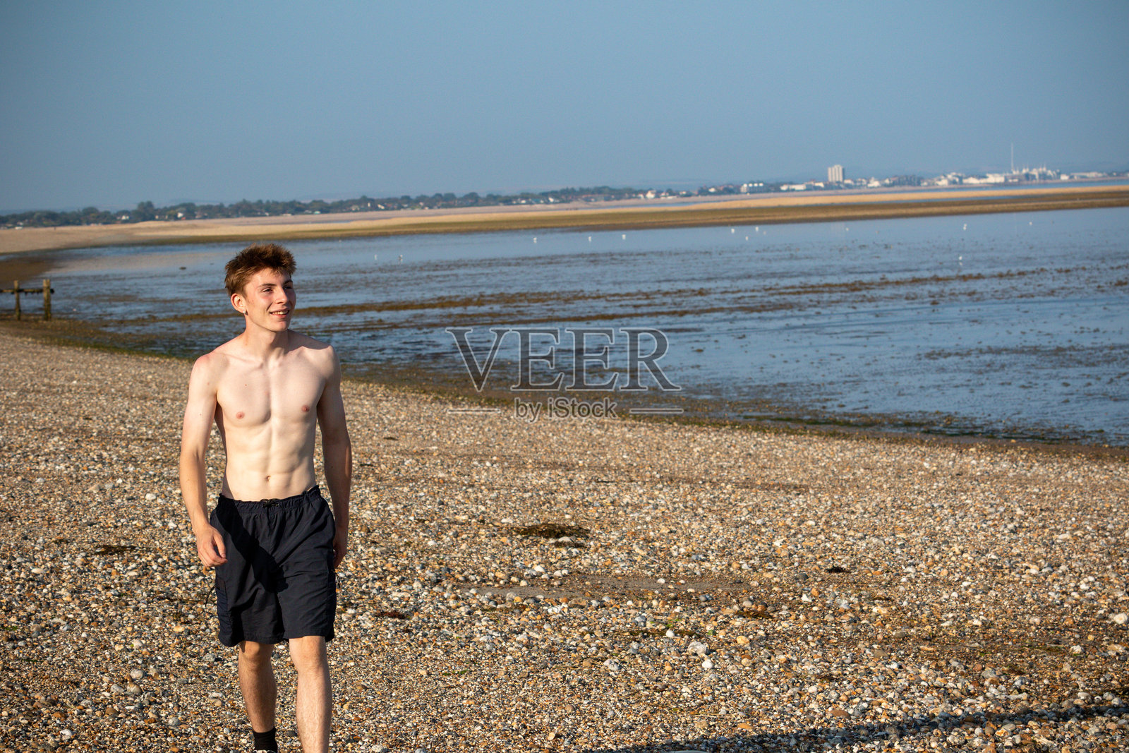 一个十几岁的男孩在户外行走,镜头采用风景照的拍摄手法。照片摄影图片