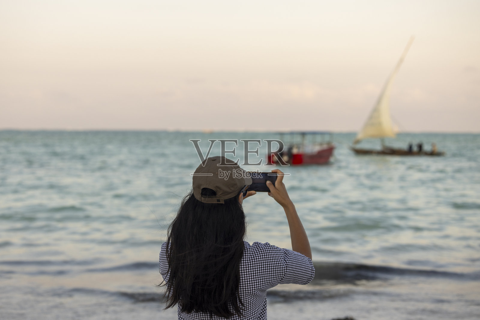 一位女士正在拍摄海滩的照片照片摄影图片