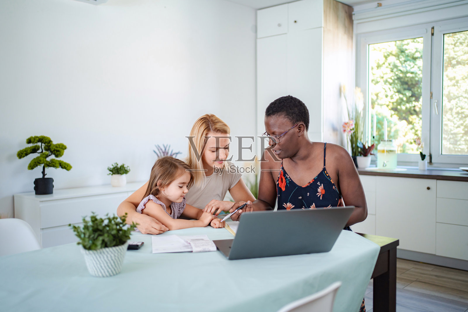 母亲和女儿在家与家教一起使用笔记本电脑学习照片摄影图片