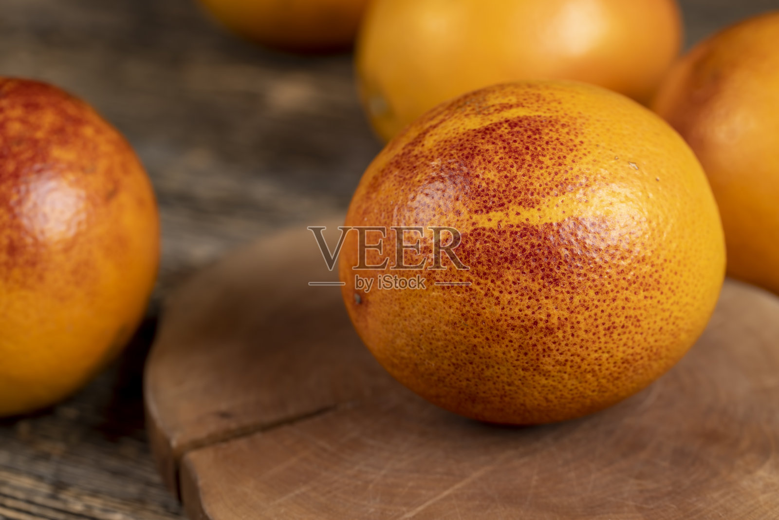 木桌上切开的鲜红橙色橙子,果肉多汁,桌上摆放着颜色不寻常的鲜甜红橙。照片摄影图片