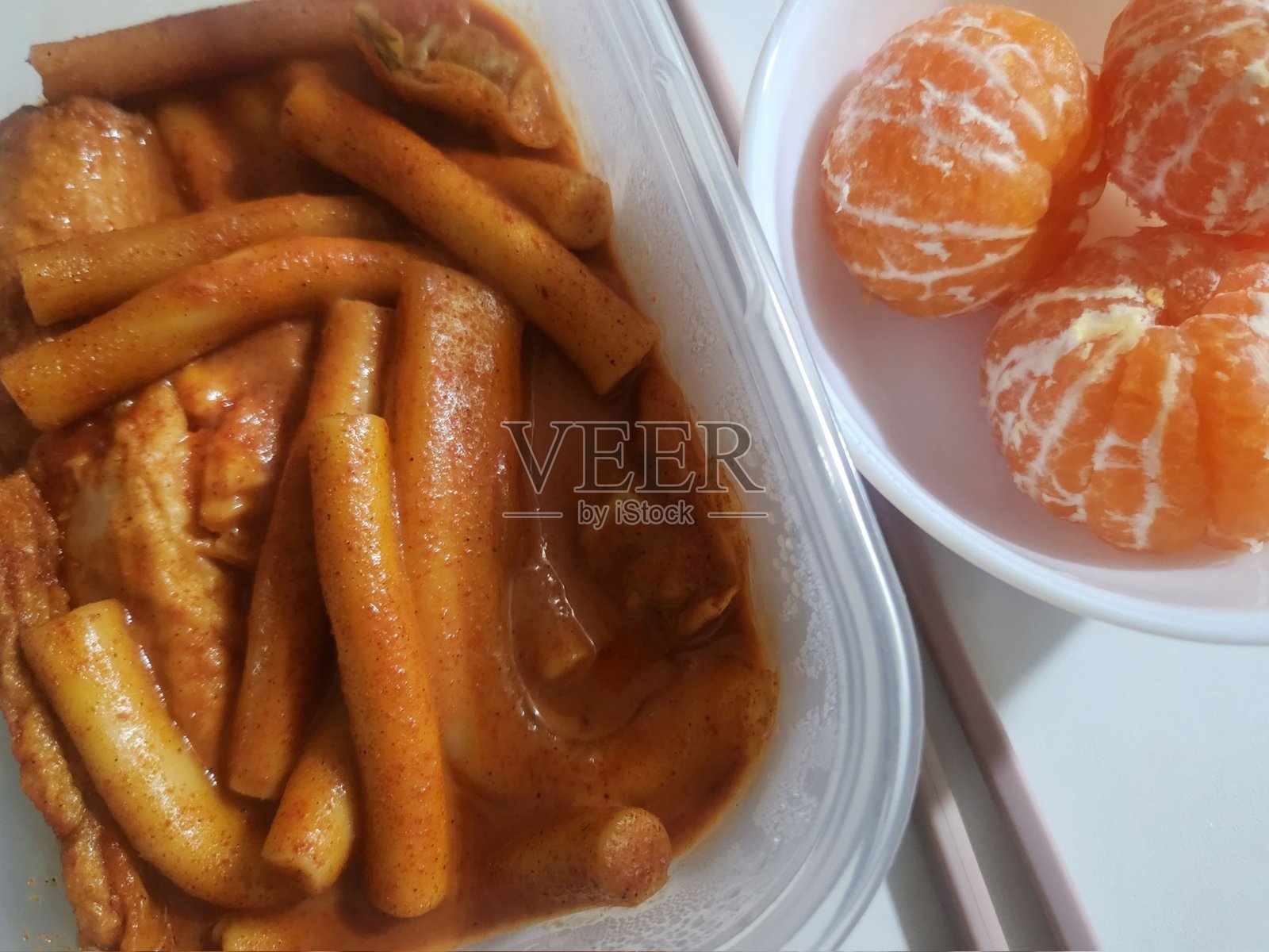 辣味炒年糕,配有浓郁红酱中的Q弹年糕,旁边搭配去皮的橙子,在浓郁的咸鲜味和甜美清爽的柑橘类水果之间形成鲜明对比。照片摄影图片