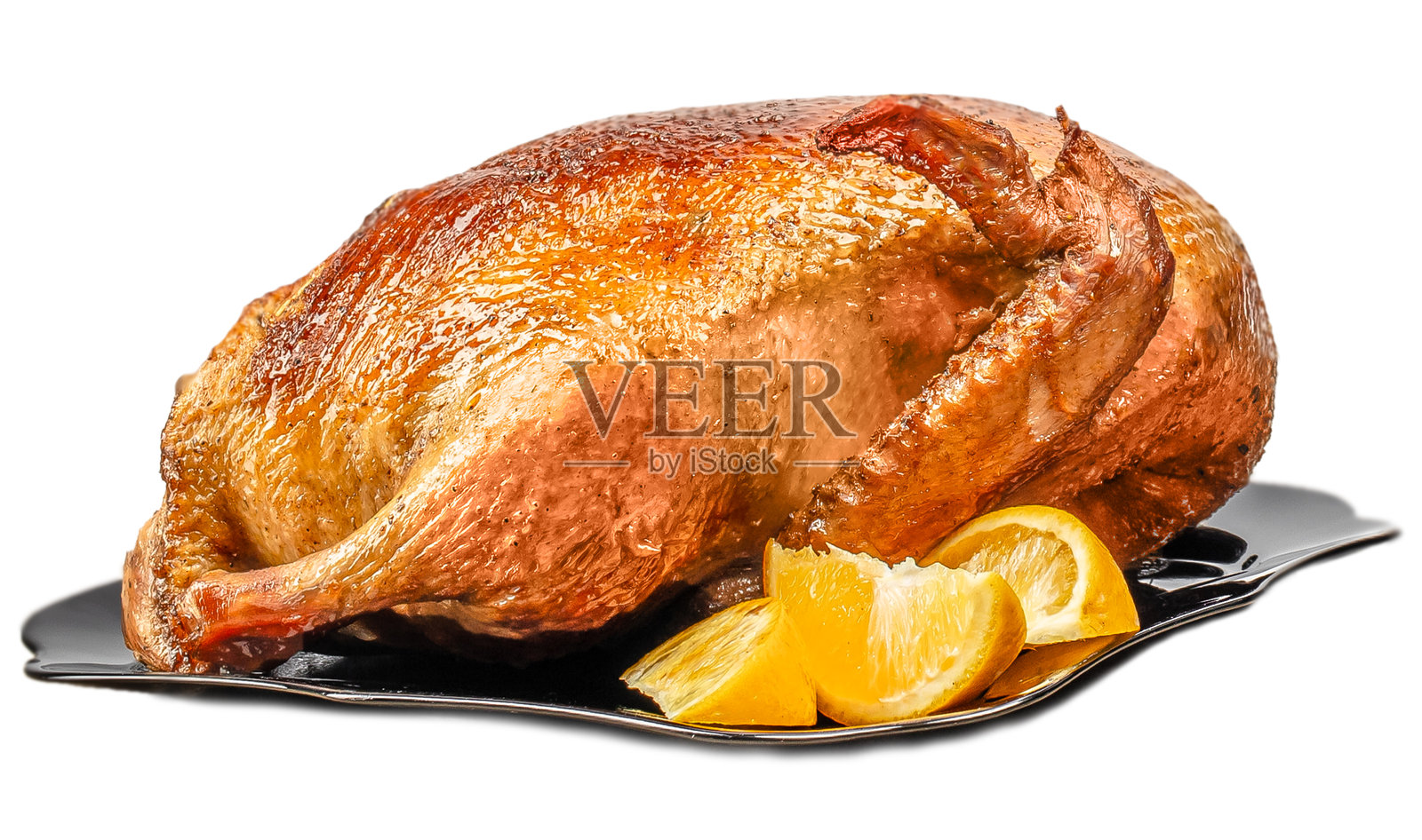 一只烤得金黄酥脆的全烤鸭摆在盘子里,配有柠檬片,孤立在白色背景上照片摄影图片