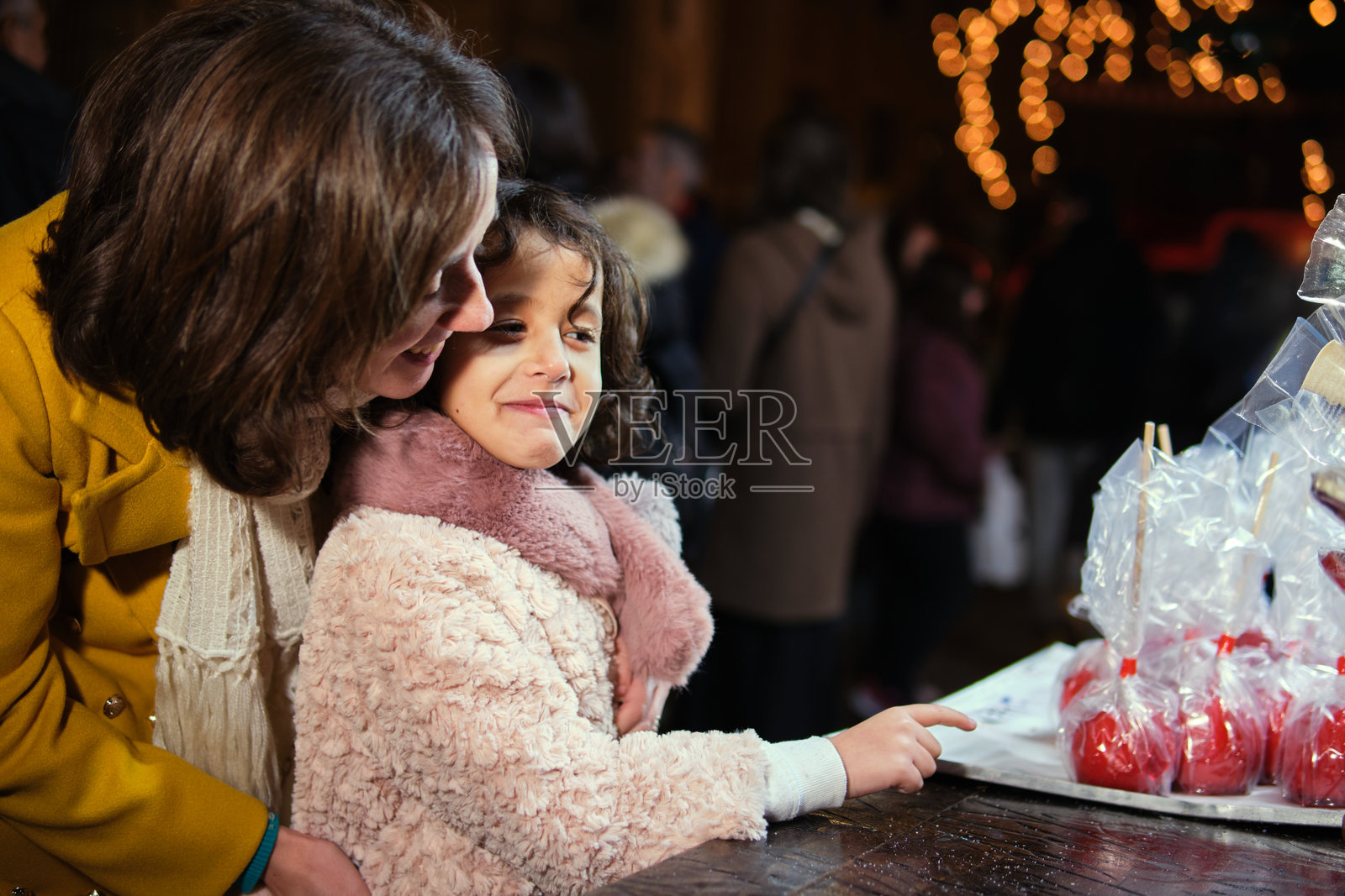 夜晚,父亲在节日的圣诞广场上扛着女儿的肩膀照片摄影图片