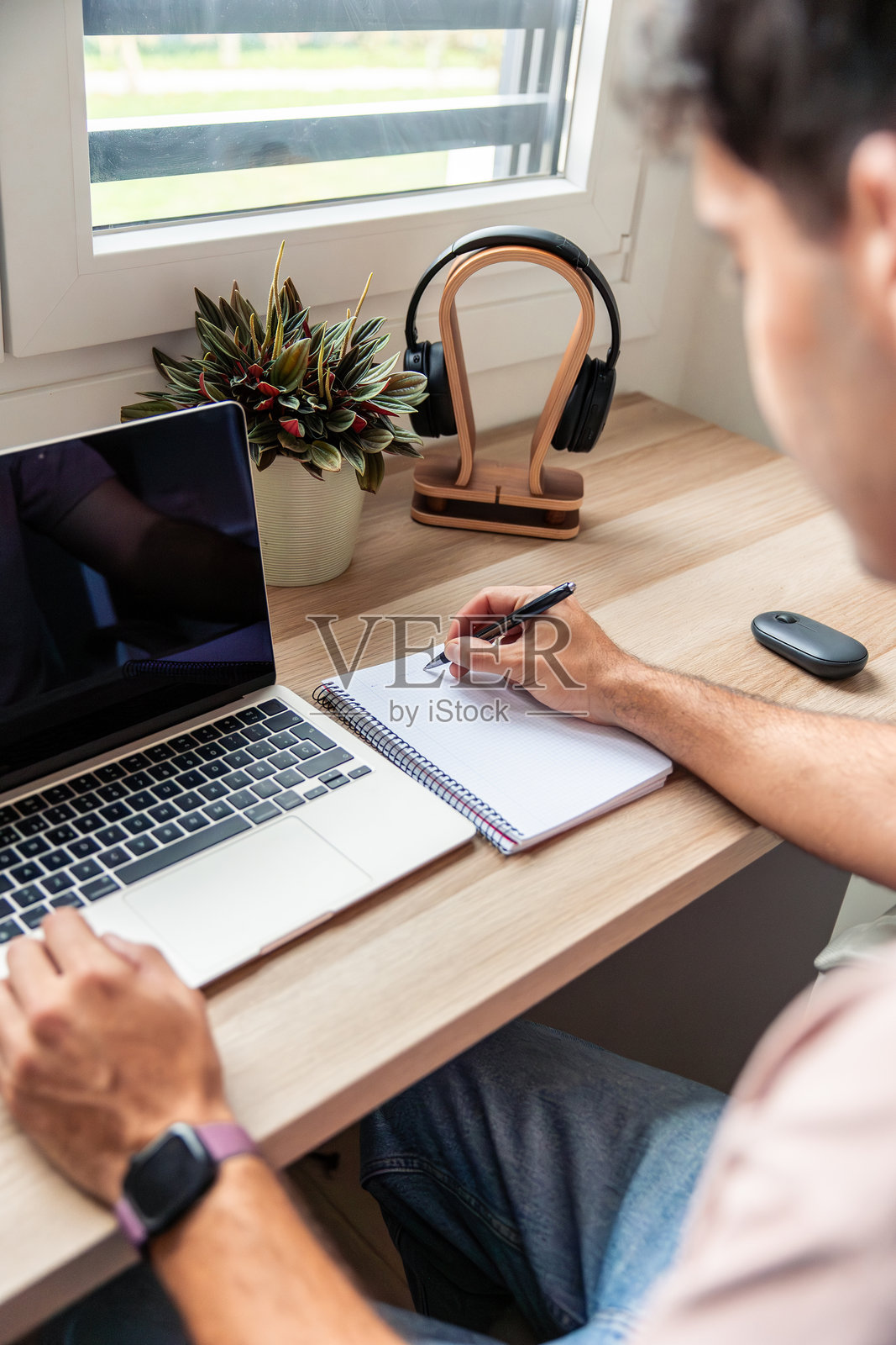 年轻男子在家远程办公,在书桌前写笔记照片摄影图片