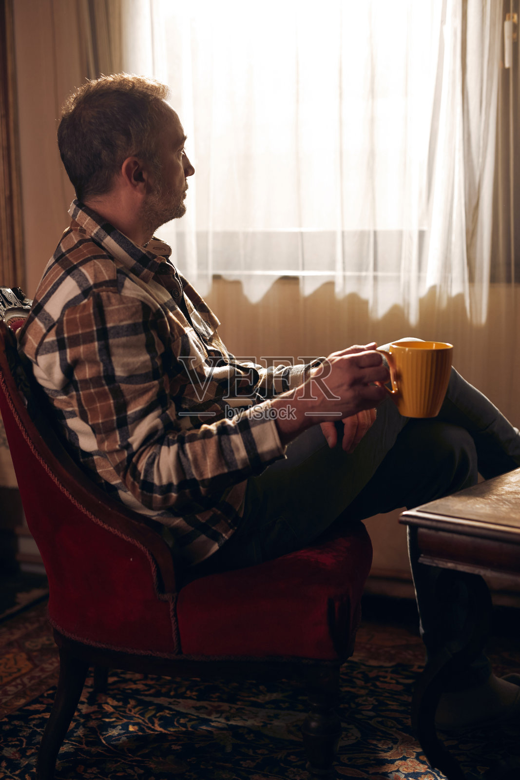 秋冬季节,男人在家中拿着一个黄色的杯子。照片摄影图片