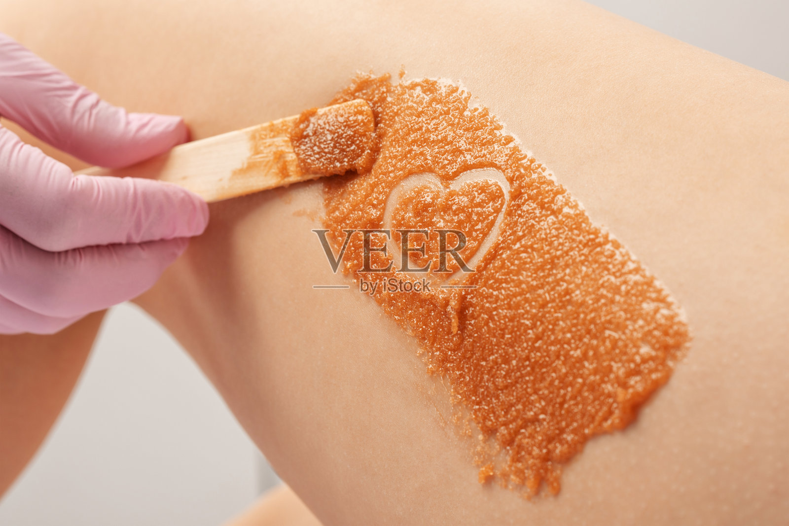 美容师正在为女性大腿进行美容去角质护理。美容院的水疗护理。照片摄影图片