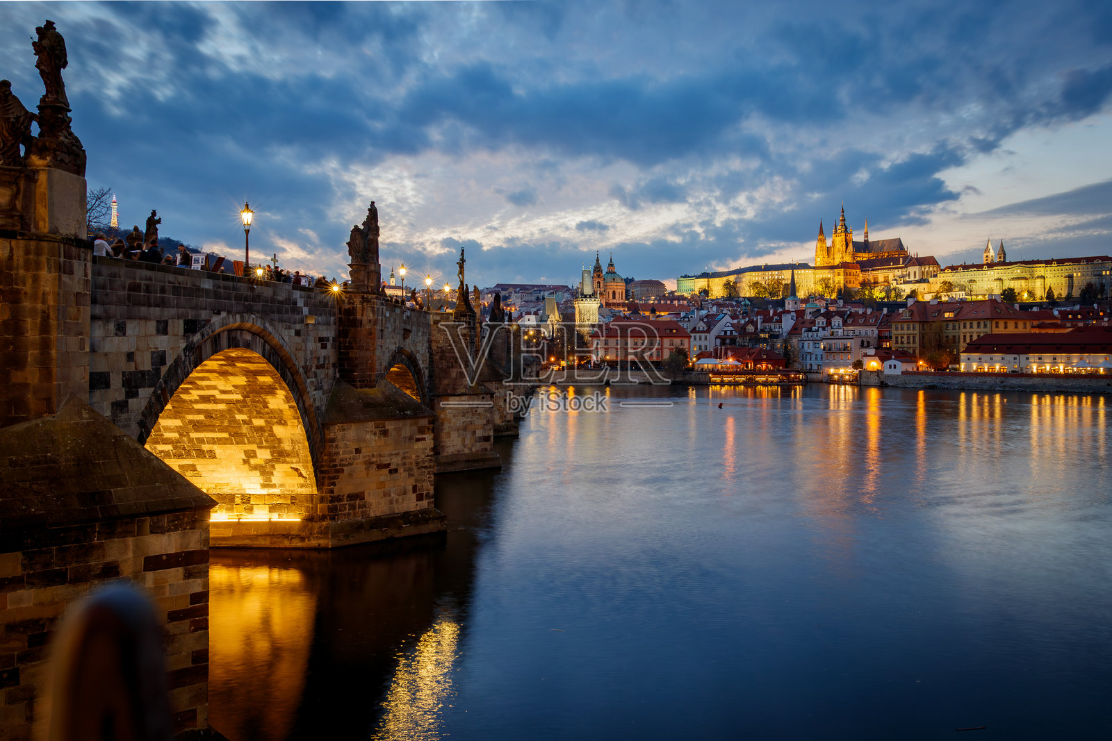 查理大桥在蓝色时刻被照亮,布拉格城堡倒映在伏尔塔瓦河上照片摄影图片