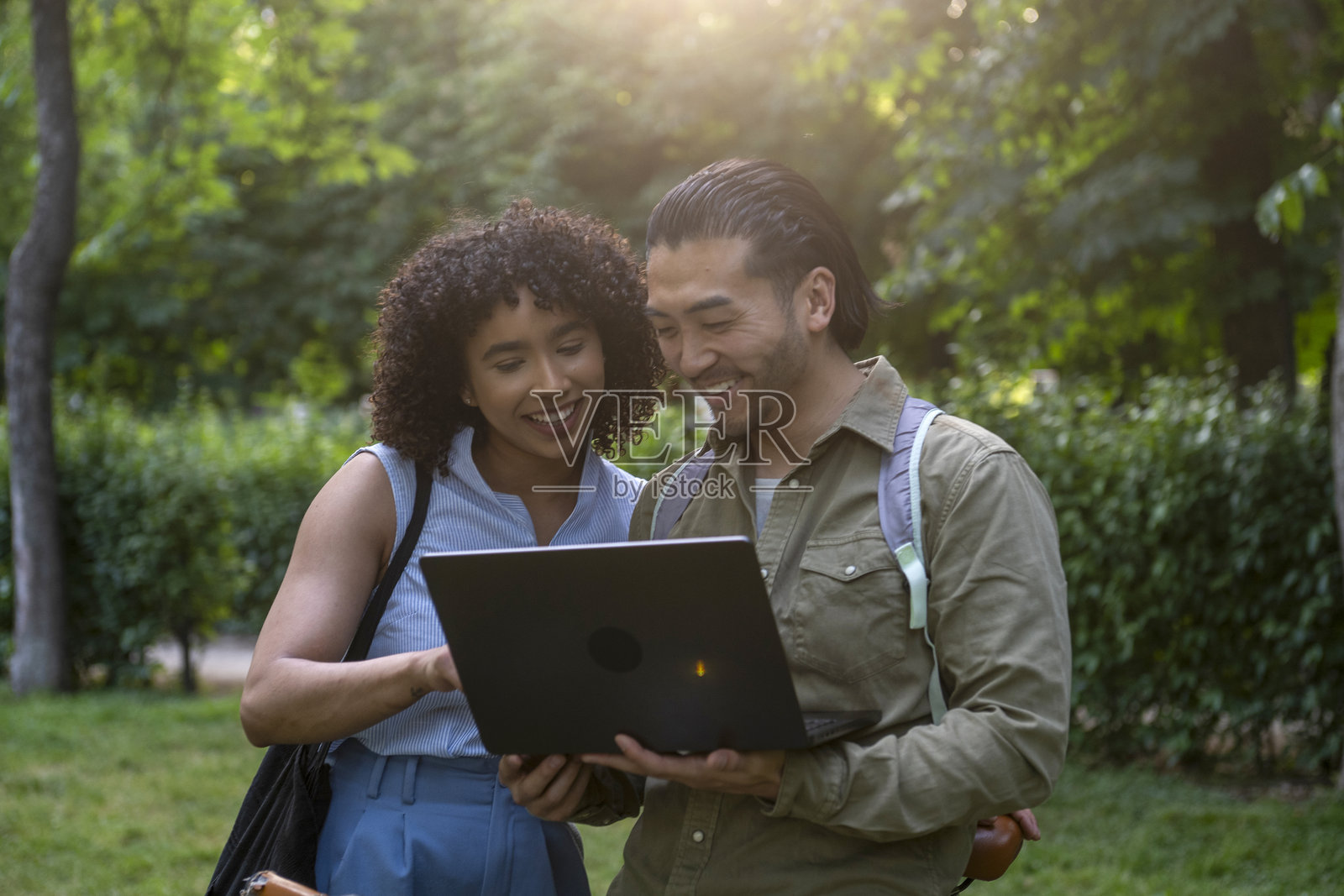 在公园里使用笔记本电脑的跨种族情侣照片摄影图片