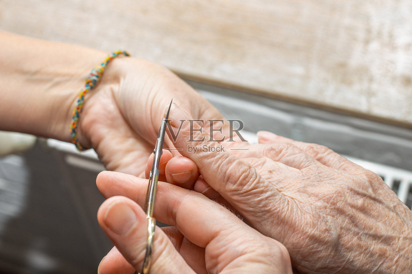 护理人员用指甲剪为一位年长女性修剪指甲,特写镜头。关爱体弱老人。照片摄影图片