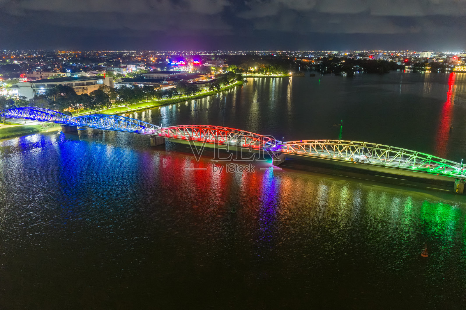 夜色下的顺化市长钱桥全景。桥梁灯火辉煌,水面有模糊的倒影。照片摄影图片