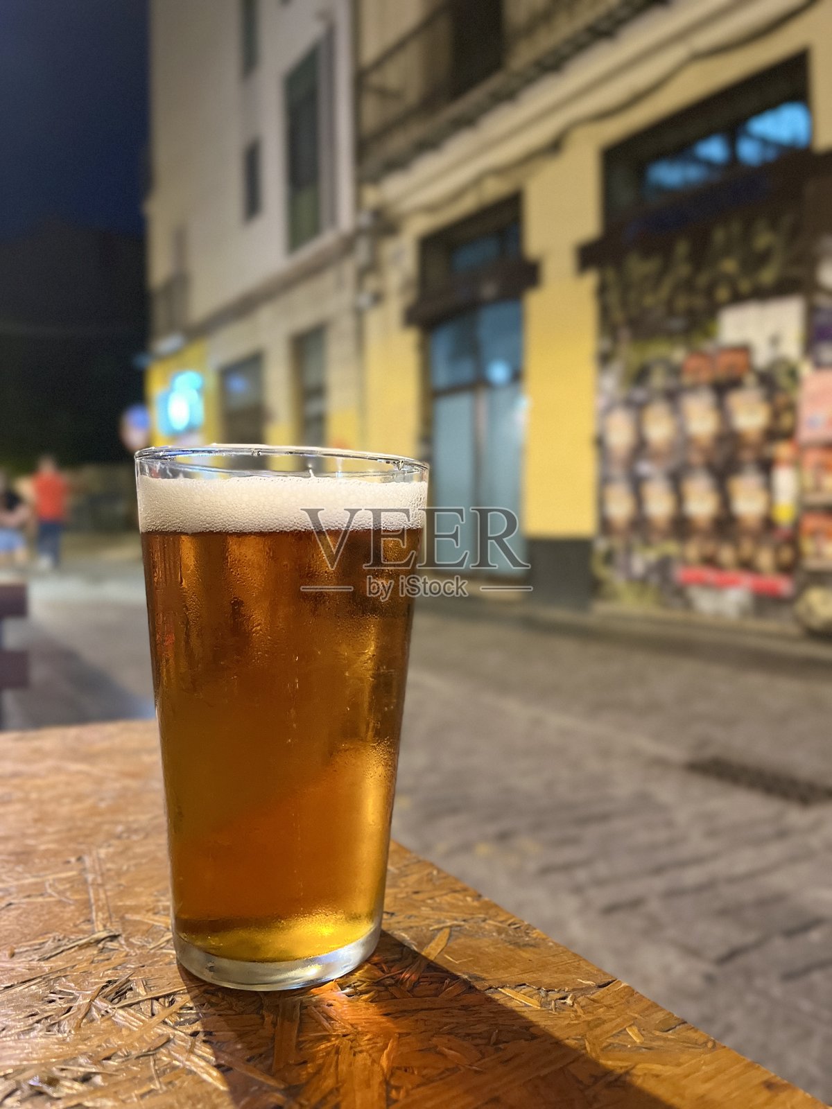 在西班牙瓦伦西亚的阿尔塔街(Calle Alta)享受夏夜假期,一杯清爽的啤酒,体现了旅行与放松的概念照片摄影图片