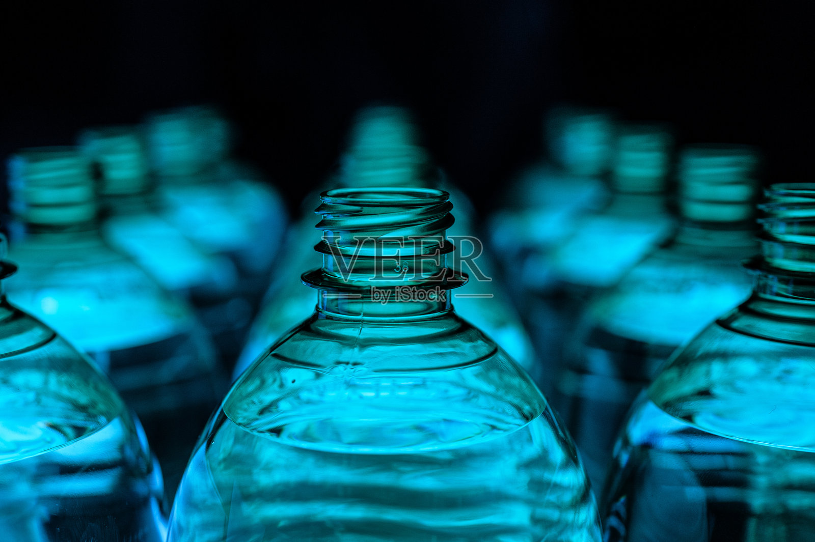 黑色背景上排成一列的蓝色塑料瓶照片摄影图片