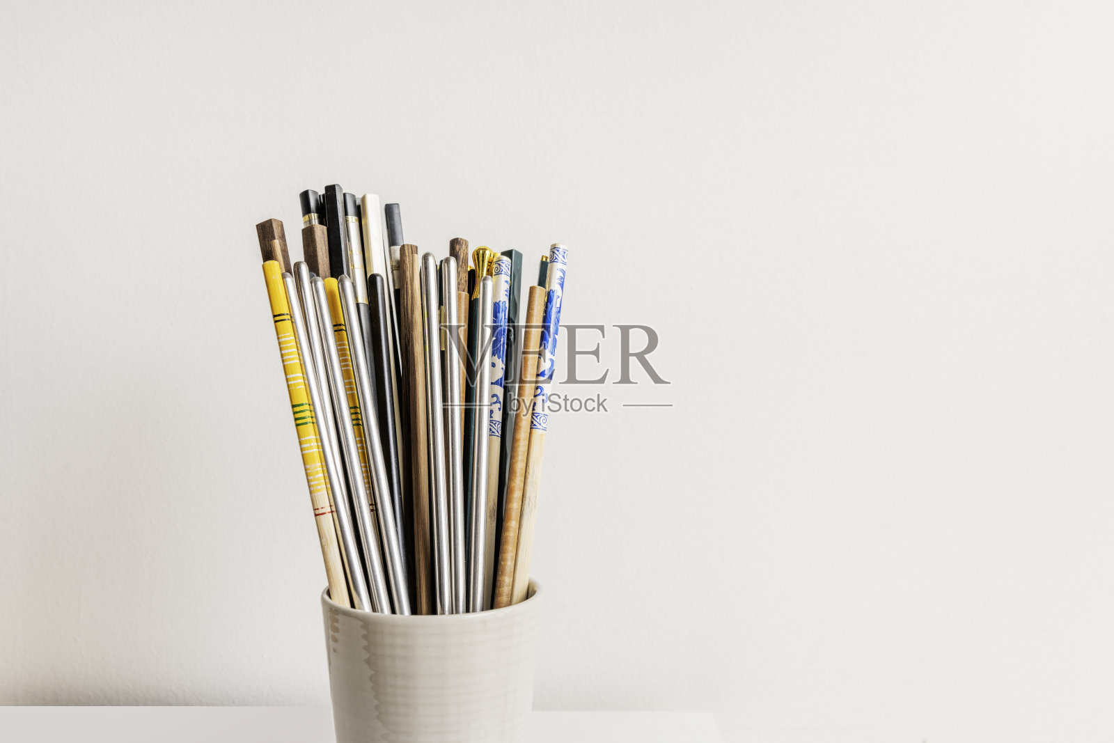 一个浅色的瓷器容器,里面装有木质餐具筷子和其他材料照片摄影图片