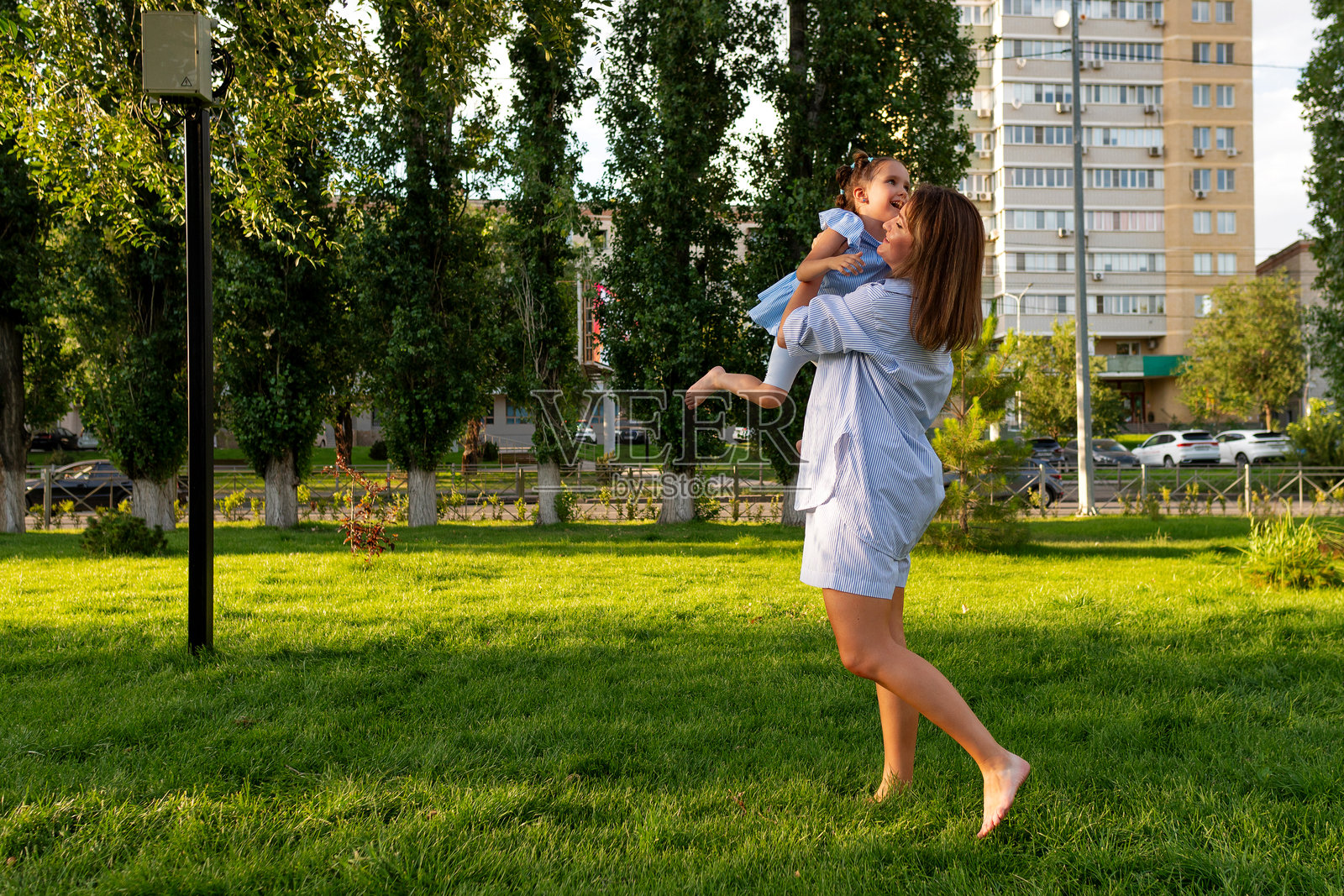 妈妈在阳光明媚的城市公园里,开心地转着她大笑的女儿照片摄影图片