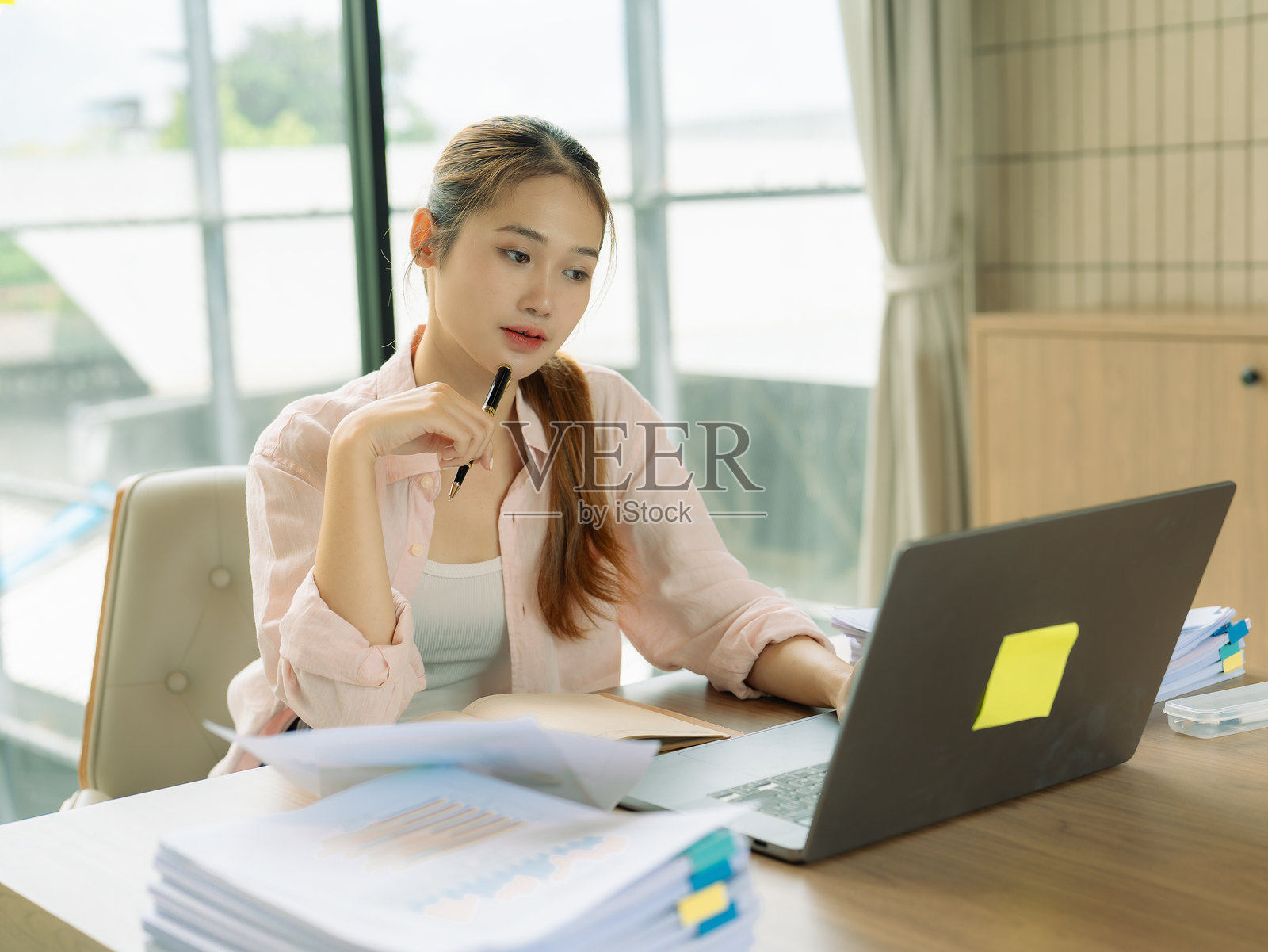 一位穿着休闲的可爱年轻女子在客厅使用电脑参加在线会议。营造出舒适氛围的居家办公概念。照片摄影图片